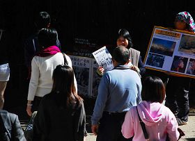 法轮功学员有的拿着展板,有的向中国大陆游客讲真相