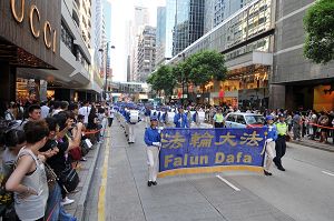 法轮功反迫害游行队伍由天国乐团领头,步入广东道,马路两旁站满了观看和拍照的市民及游客。