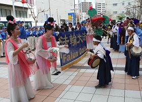 天国乐团在旗头阵现场演奏，仙女并发送系有“法轮大法好”卡片的莲花书签。