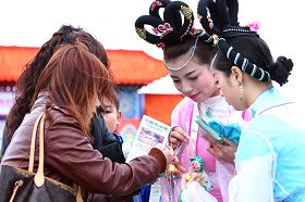 民众除了拿着仙女队仙女送的莲花,同时也拿法轮功简介。